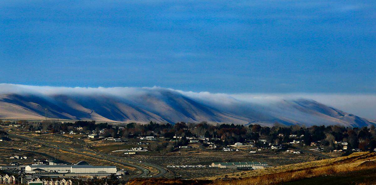 Low clouds roll over the Horse Heaven Hills in Badger Canyon behind the Rancho Reata housing development and west toward Benton City.