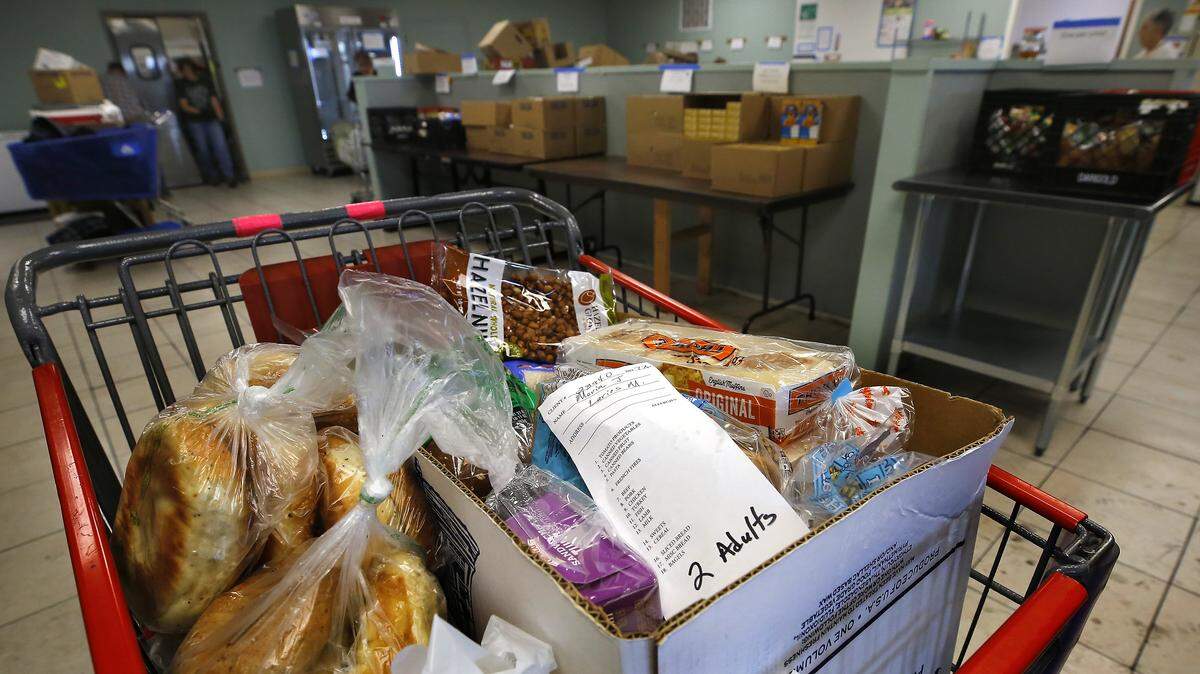 A grocery cart is filled with food for a client with needs for two adults recently at the Kennewick branch of the Tri-Cities Food Bank. 