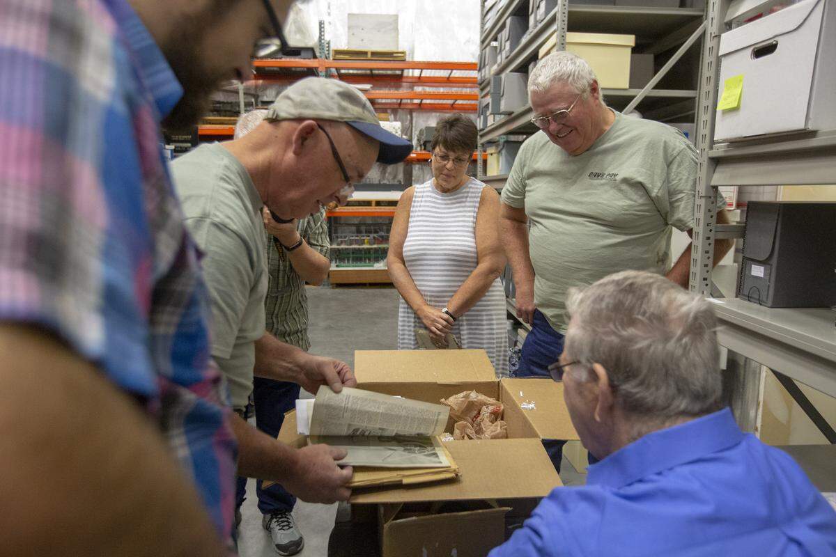 Local historians gather around a box in front of Wyatt Wineinger, center, inside WSU Hanford History Project offices in Richland on Wednesday. The box contains donated artifacts that belonged to Arlys “Duane” Wineinger, a World War II pilot of the B-17 named Day’s Pay.