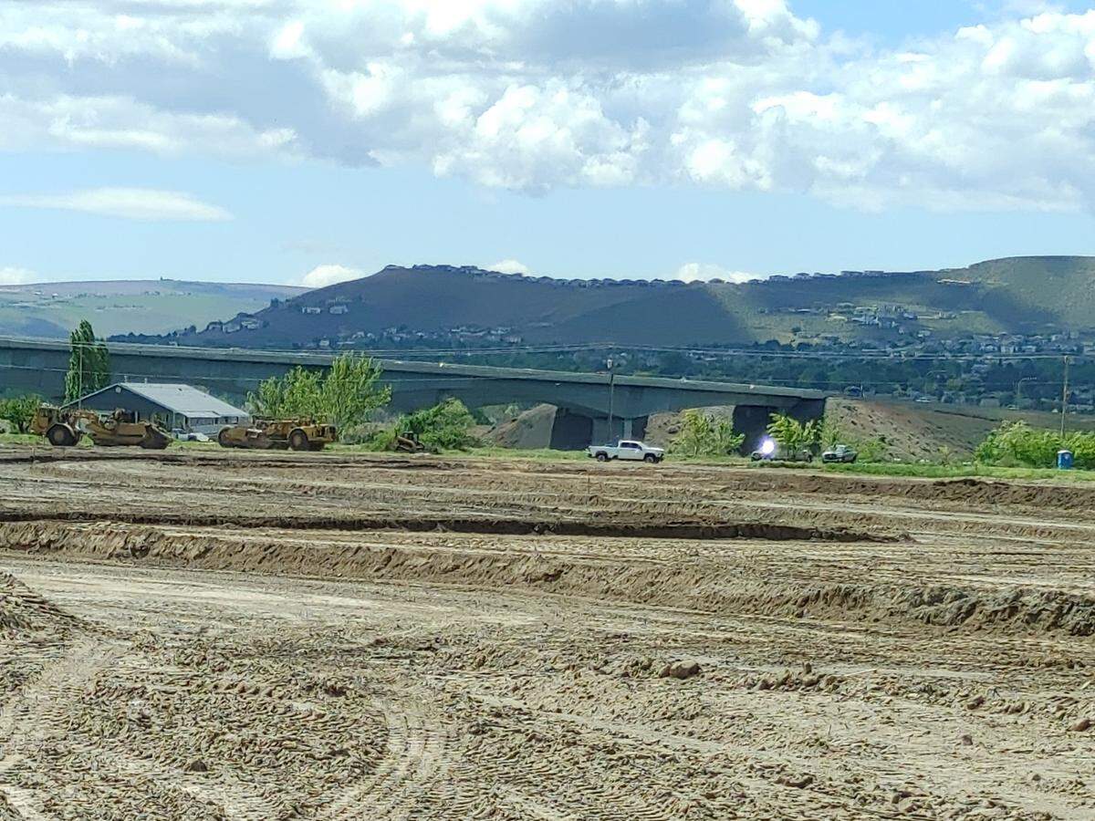 Columbia Shores will install 498 townhomes and three single family homes at the former Harris Farm, on West Court Street in Pasco. Graders move past a blue house that once belonged to the Harris family that farmed there for generations. The I-182 Glenn C. Lee/Sam Volpentest bridges are visible in the background.