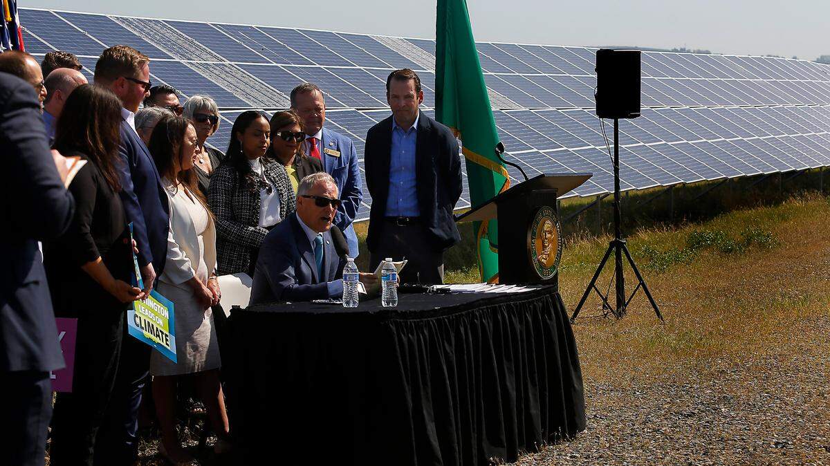Washington Gov. Jay Inslee prepares to sign a series of climate-related bills Wednesday morning at the Horn Rapids Solar Farm, a collaborative solar energy, storage and training facility in Richland. Inslee, who announced this week he’s not running for re-election next year, is surrounded by state legislators and other dignitaries during the news conference.