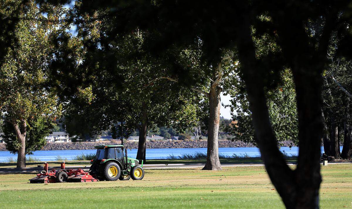 A city of Kennewick tractor pulls a mower across an expanse of grass in the east end of Columbia Park recently in Kennewick.