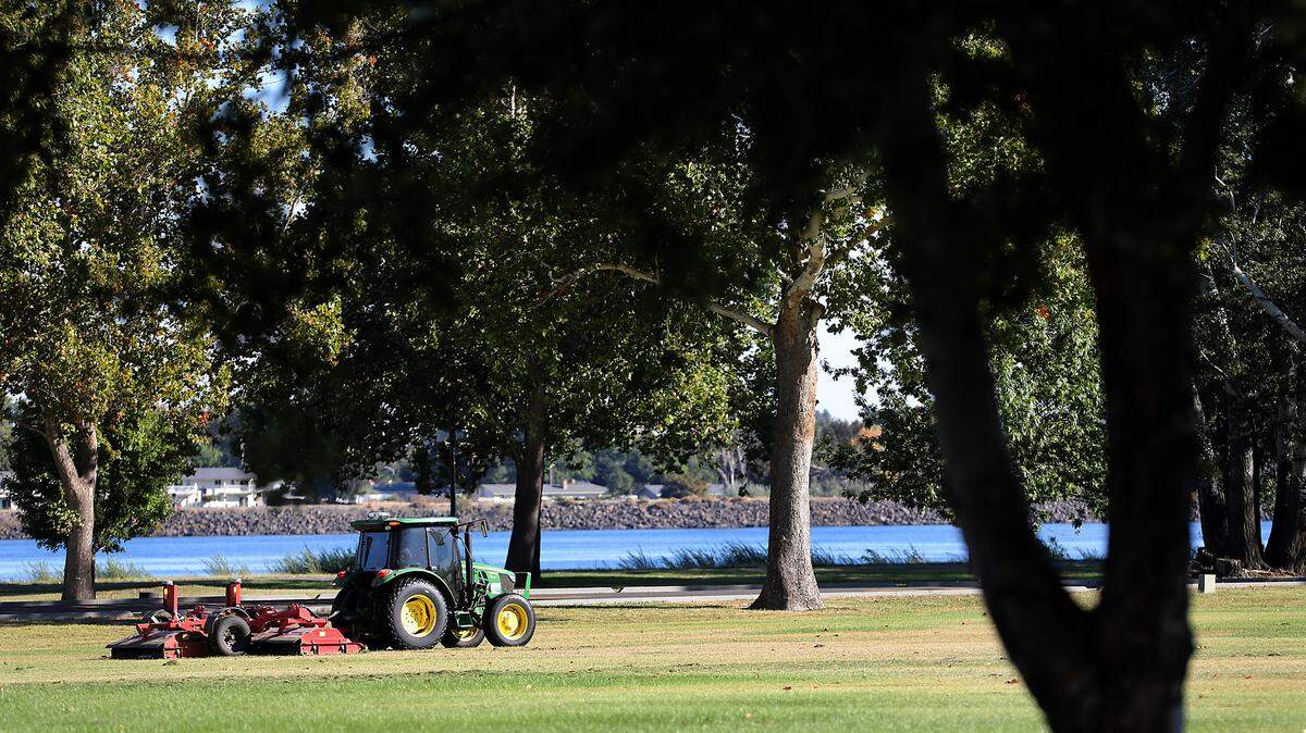 A City of Kennewick tractor pulls a mower across a field of grass in the east end of Columbia Park recently in Kennewick.