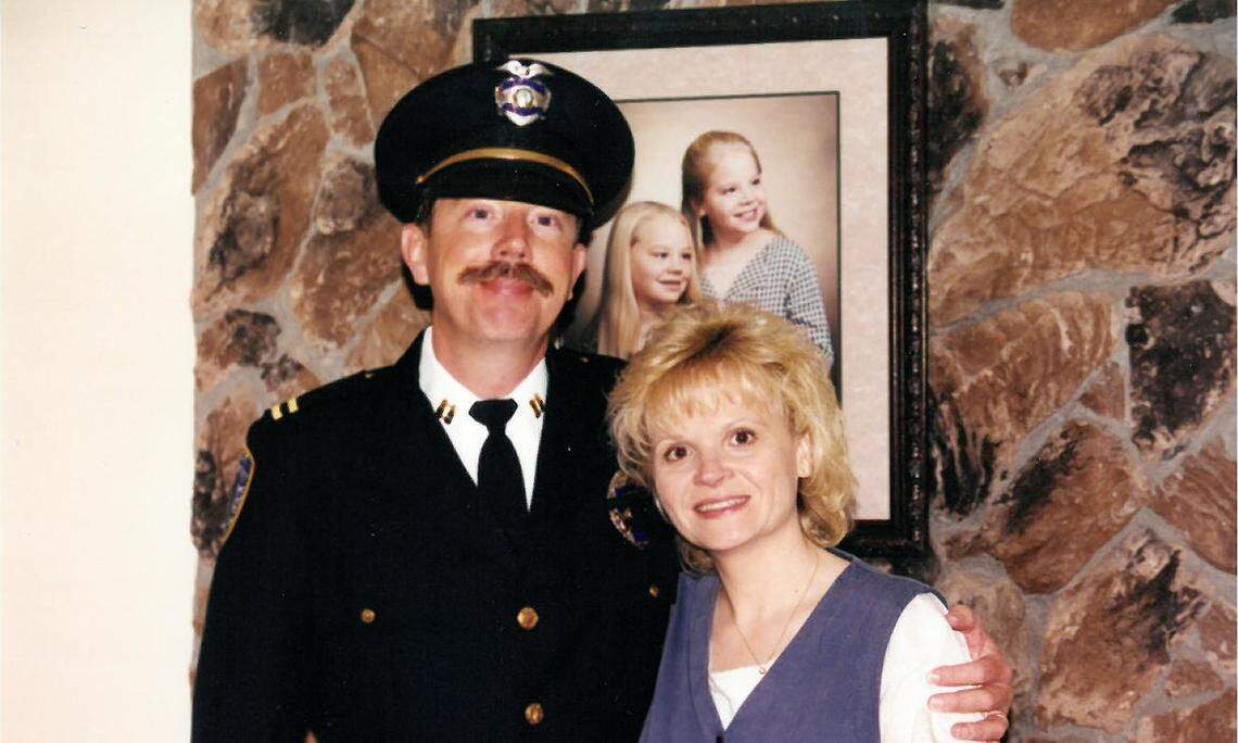 Ken and Trish Hohenberg stand in front of a picture of their daughters in 1998.