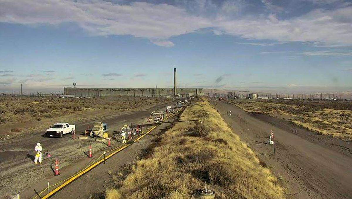 Hanford workers wearing special respirators check for radiation Friday along a waste storage tunnel after steam was seen rising from a small building connected to the tunnel. The former PUREX plant can be seen in the background.