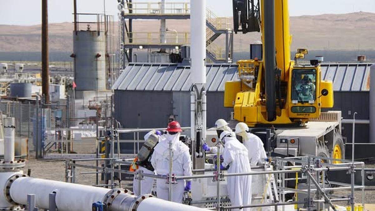 Hanford workers install a high-pressure nozzle inside an underground tank storing radioactive waste to help mix and move the sludge to prepare to transfer it for treatment at the vitrification plant.