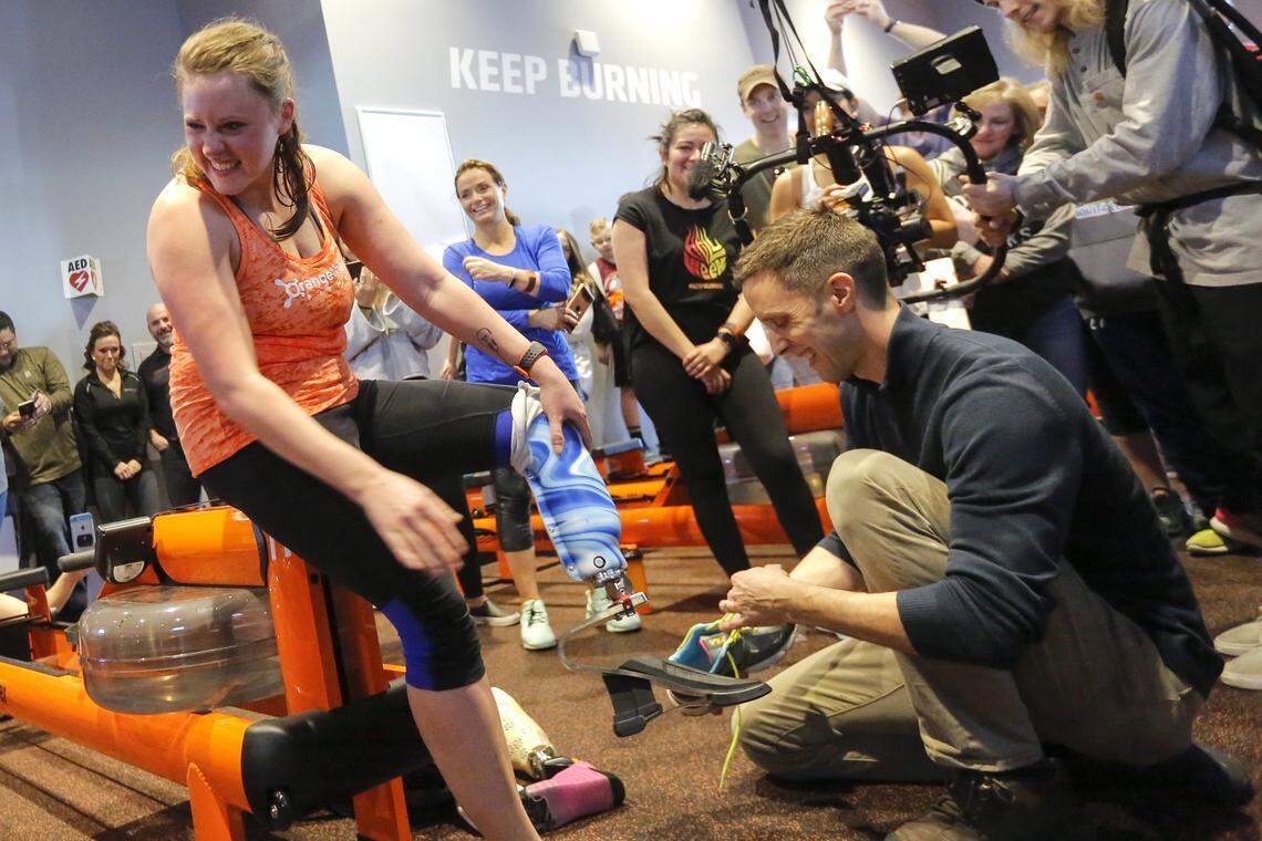 Cassi Juell, left, smiles and looks over to her husband as Kasey Johnson, left, of Columbia Basin Prosthetics & Orthotics, helps Juell with her new custom prosthetic leg inside of OrangeTheory in Richland.