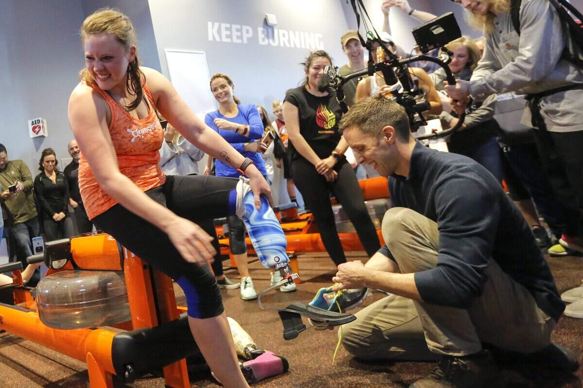 Cassi Juell, left, smiles and looks over to her husband as Kasey Johnson, left, of Columbia Basin Prosthetics & Orthotics, helps Juell with her new custom prosthetic leg inside of OrangeTheory in Richland.