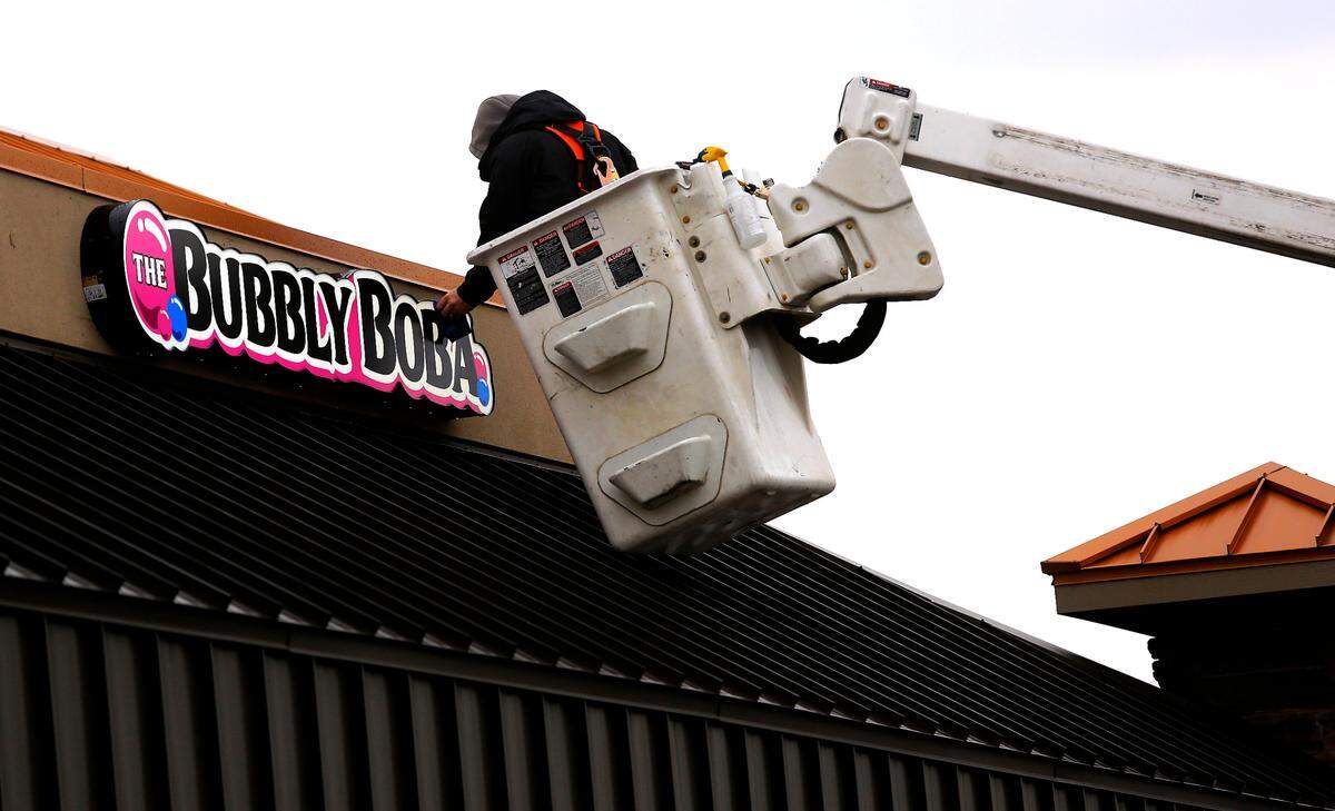 Tyler Wolf, an employee of Mustang Signs, installs a new sign for a new business called The Bubbly Boba in the Marineland Plaza of North Edison Street in Kennewick.