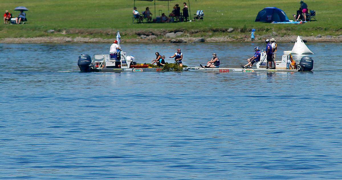 H1 Unlimited boat racing officials, wearing blue shirts at right, take to the water on a rescue sled to assess the problem of an aquatic grass clogging the boat racing lanes of the Columbia Cup race course Friday afternoon on the Franklin County side of the river. Water Follies rescue volunteers pull the grass from the water onto their watercraft in an attempt to open the course.