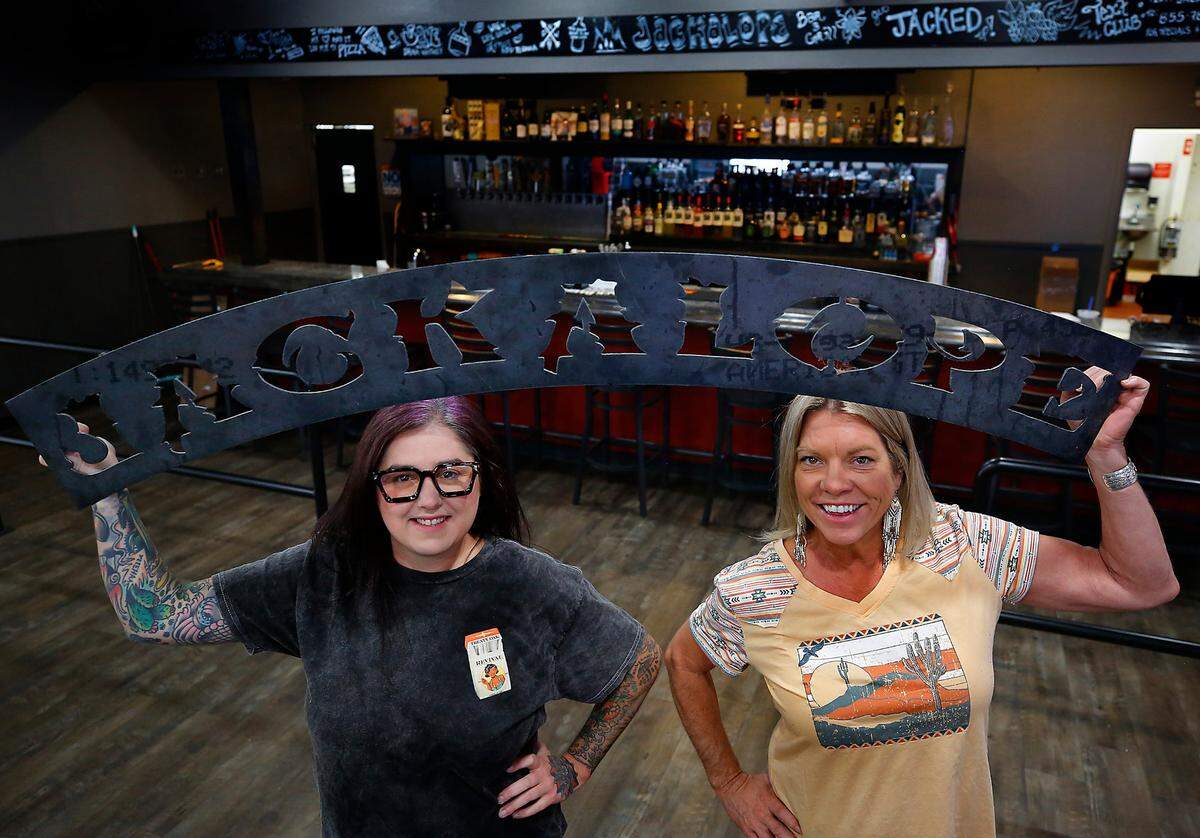 Manager Emilie Hallman, left, and Laurie Winchel Atwood, owner of Jackalope Bar & Grill, hold up a metal sign they’ll soon be installing in their new location.