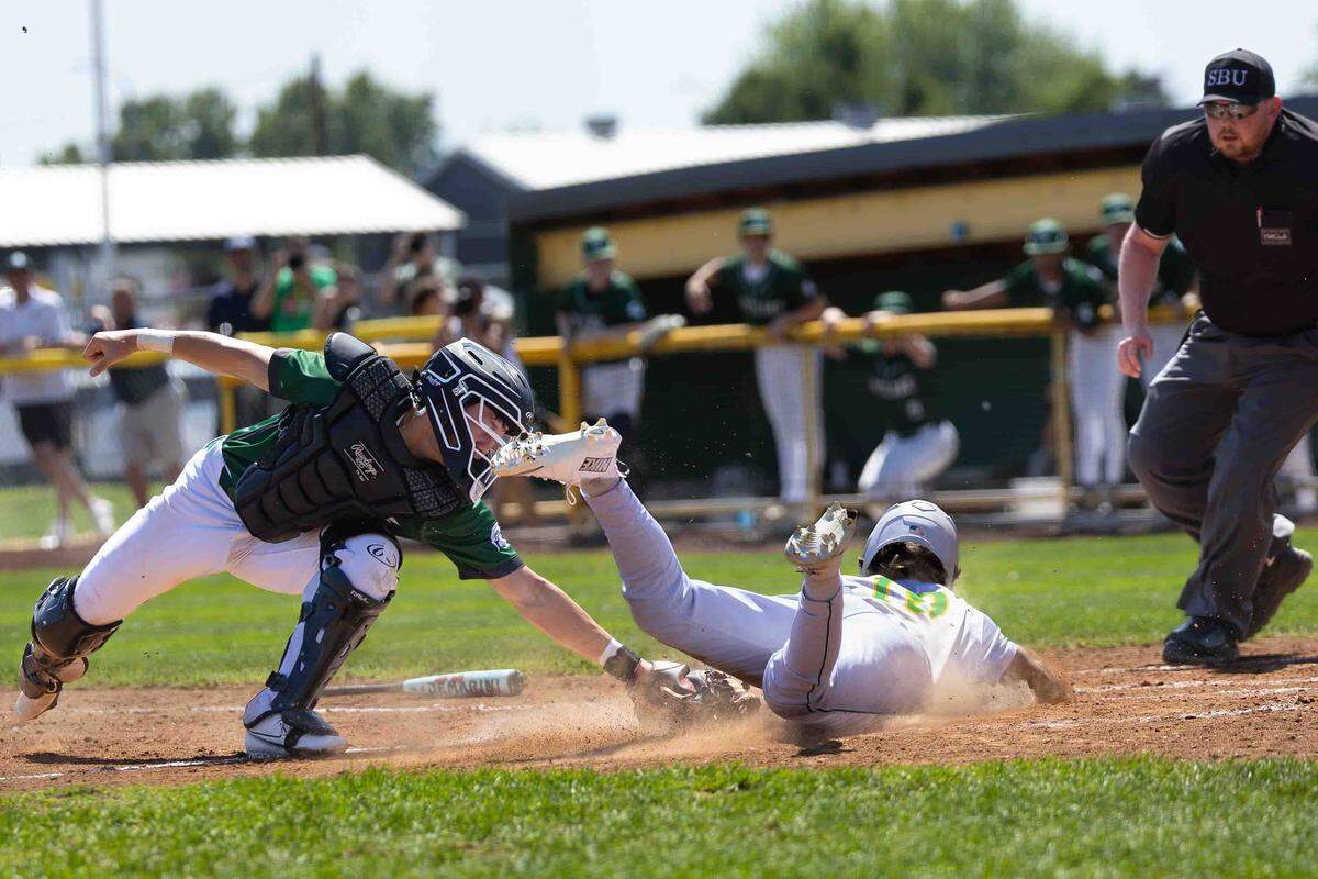 Richland Bombers junior centerfielder Parker Smoot dives safely into home plate ahead of a missed tag by Skyline catcher Andrew Yurkanin during the opening round of the WIAA 4A State Baseball Championships Saturday at Bomber Bowl in Richland. Smoot scored one of two runs in the Bombers’ 2-0 victory that helped send Richland into the state semifinals.