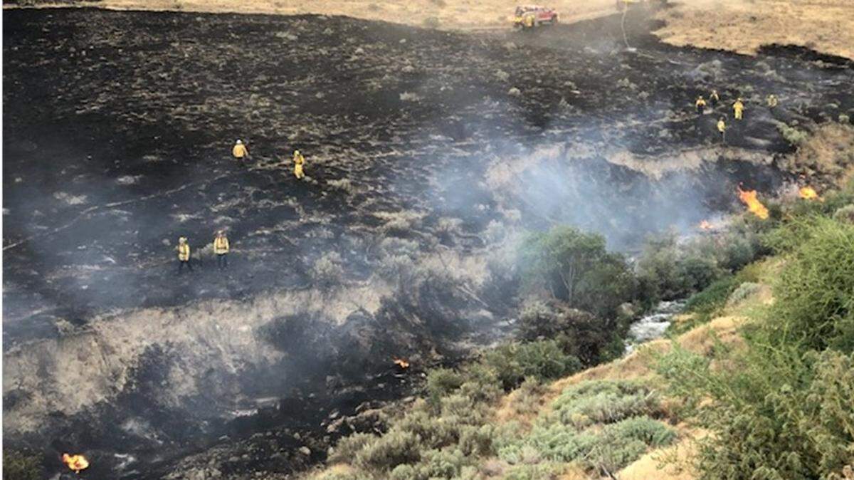 Firefighters search for hot spots after a fire broke out near Bob Olson Parkway Tuesday afternoon.