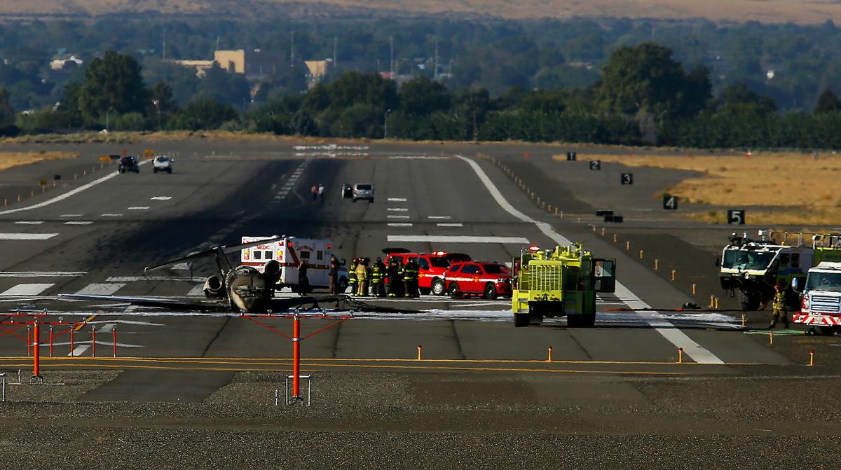 The charred remains of a privately owned small jet airplane rests on a runway surrounded by emergency vehicles on Sept. 20, 2022 at the Tri-Cities Airport in Pasco.