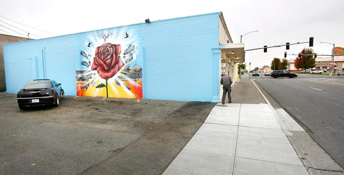A customer walks to Vinny’s Bakery past the remaining section of the Community Hope Wall mural that was painted in November 2019 on the side of the building on Lewis Street near 10th Avenue in Pasco.