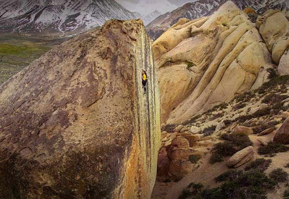 Nina Williams climbing a tall boulder face in Arizona.