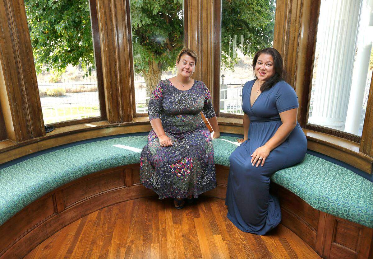 Sandrine King, left, and Lisette Conde, new co-owners of the Moore Mansion, sit on the recently refurbished original curved seating near the bay windows in the living room of the historic building along the Columbia River in Pasco.