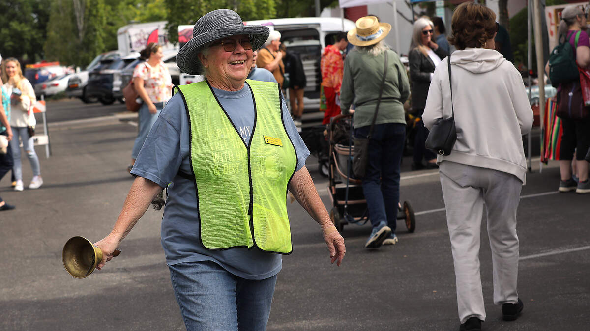 Kathy Hanson, Richland Farmers Market manager, gives a friendly smile to vendors and customers as she walks through the venue Friday morning ringing a bell to signify the opening of sales.