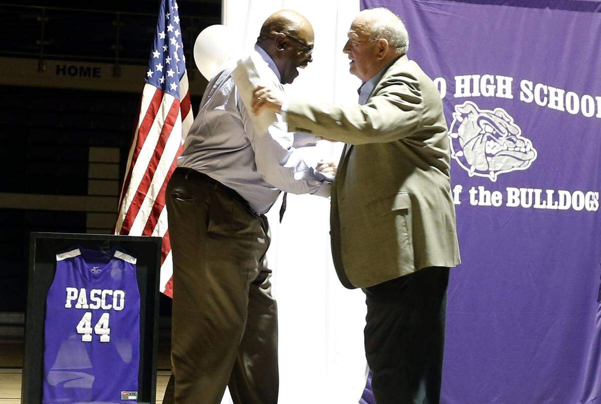 Ron Howard, left, lformer Pasco High School football player and NFL retiree, greets former basketball coach Don Monson at the Pasco gym.  Howard was honored, and the school received a golden football in his name.