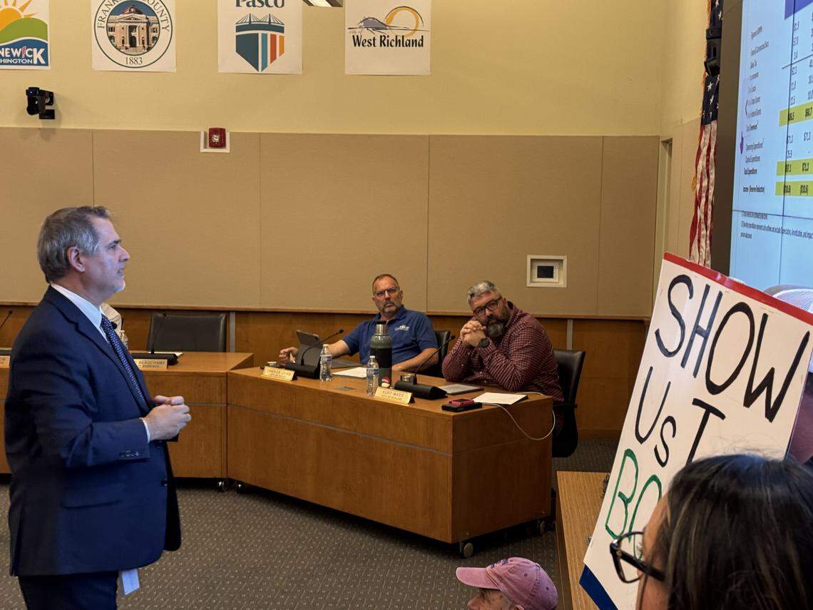 A former Ben Franklin Transit employee placed a sign that reads “show us the books!” in front of CEO Thomas Drozt as he presented the agency’s 2026 budget on Dec. 11, 2025.