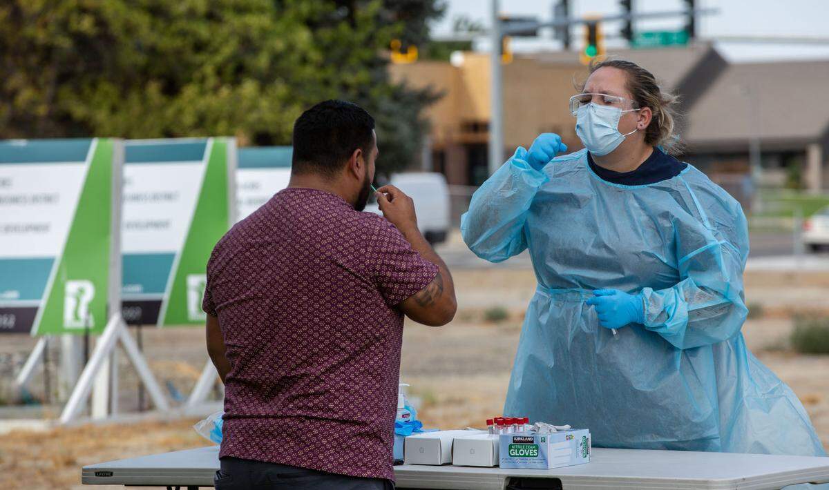 Ariel Smith, an EMT with Columbia Safety, demonstrates how to use a nose swab for a patient at the free COVID testing site off of George Washington Way. The site is closing Wednesday.