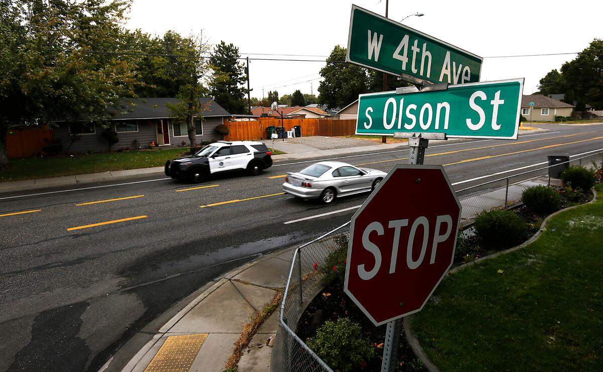 Early morning traffic, including a Kennewick Police patrol car, drives through the 3700 block of West Fourth Avenue where Kennewick detectives responded Thursday night to investigate the death of a man found shot in a home. Police officials say the death is a homicide.