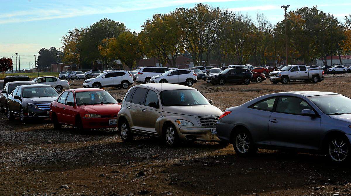 Dozens of vehicles line up in an unpaved parking area for the start of a 2nd Harvest Mobile Market food distibution near Eastgate Elementary School in Kennewick.