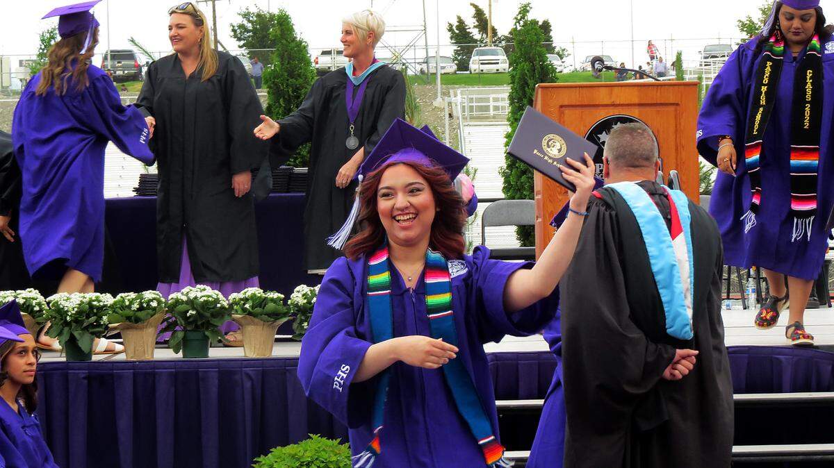 A proud Pasco High graduate shows off her diploma during the school’s outdoor commencement ceremony at Edgar Brown Stadium in Pasco.