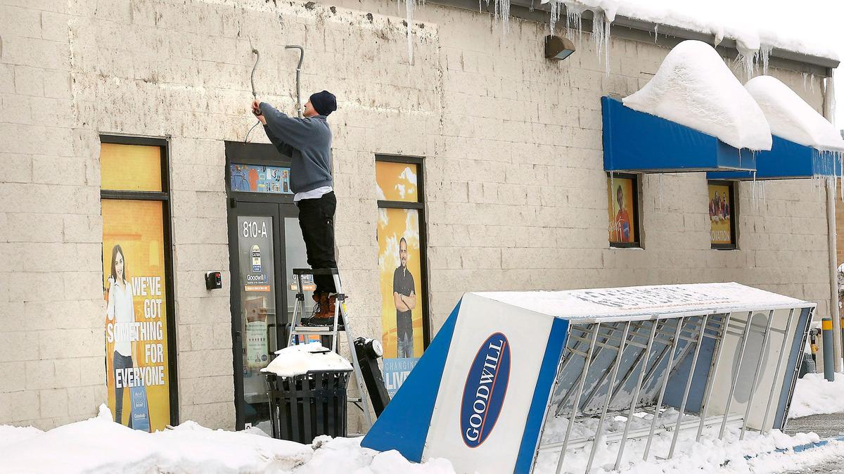 A maintenance worker for Goodwill Industries of the Columbia tapes the electrical connections Monday morning for lighting to an awning that gave way under the weight of drifting snow from the weekend’s winter storm.