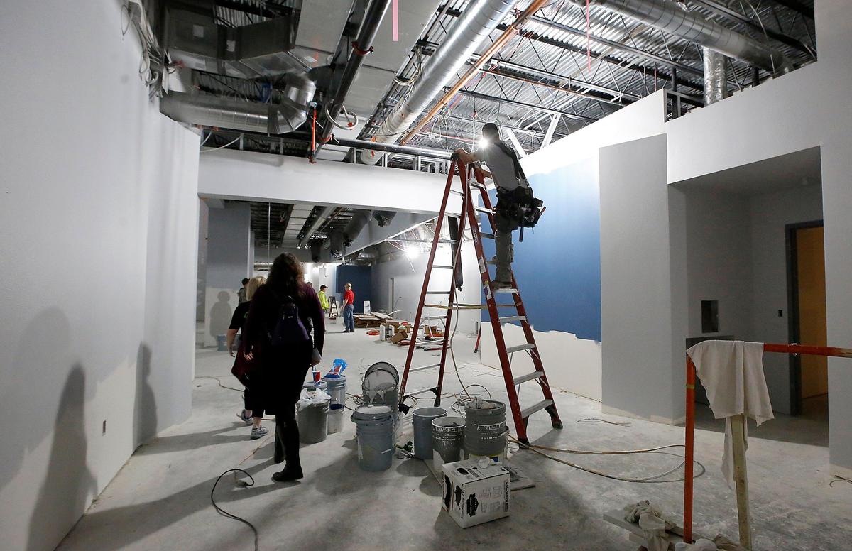 Visitors walk around construction workers busy with interior finish work Monday for the new Fairchild Cinemas at Southgate building in Kennewick. The 10-screen movie theater is expected to open in early November.