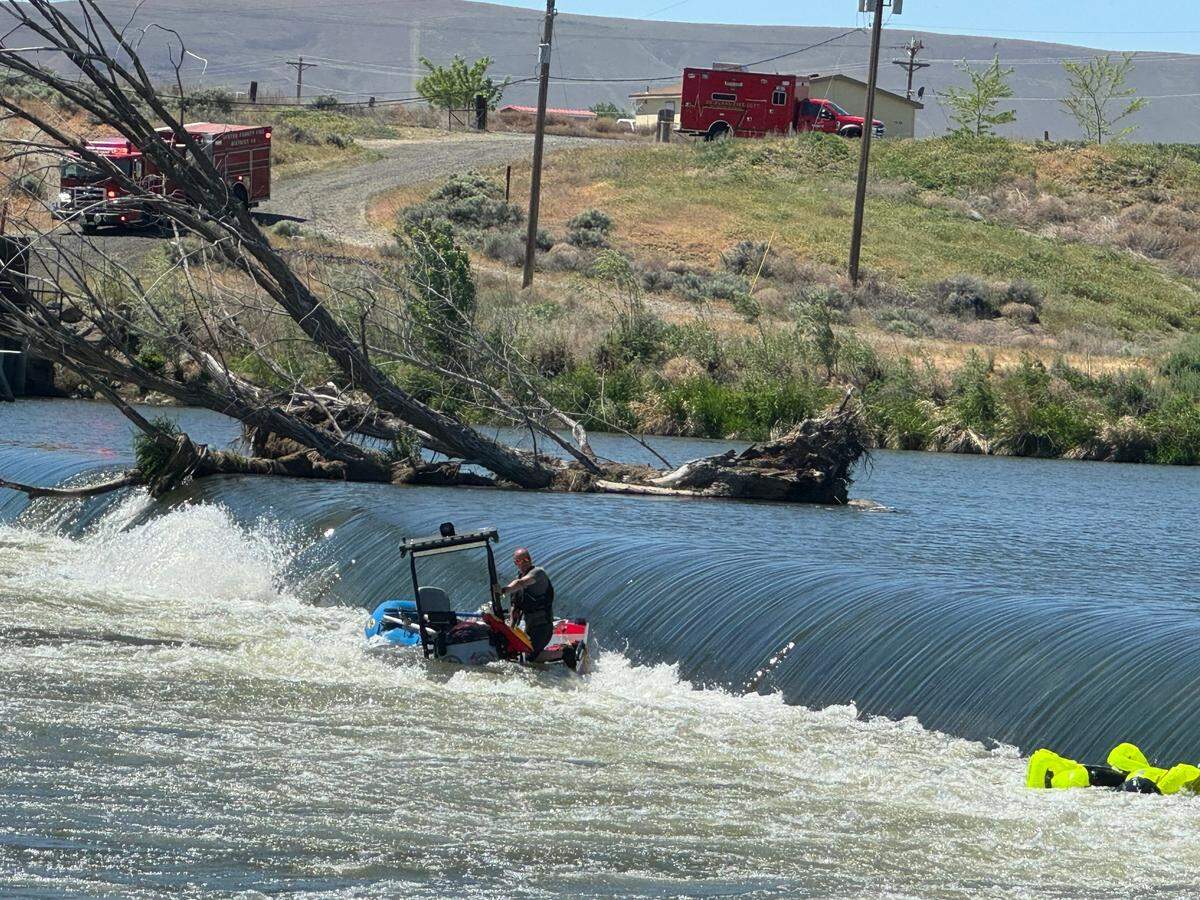 A crew member from Benton County Fire District 2 stands on a rescue boat near the Wanawish Dam on the Yakima River.
