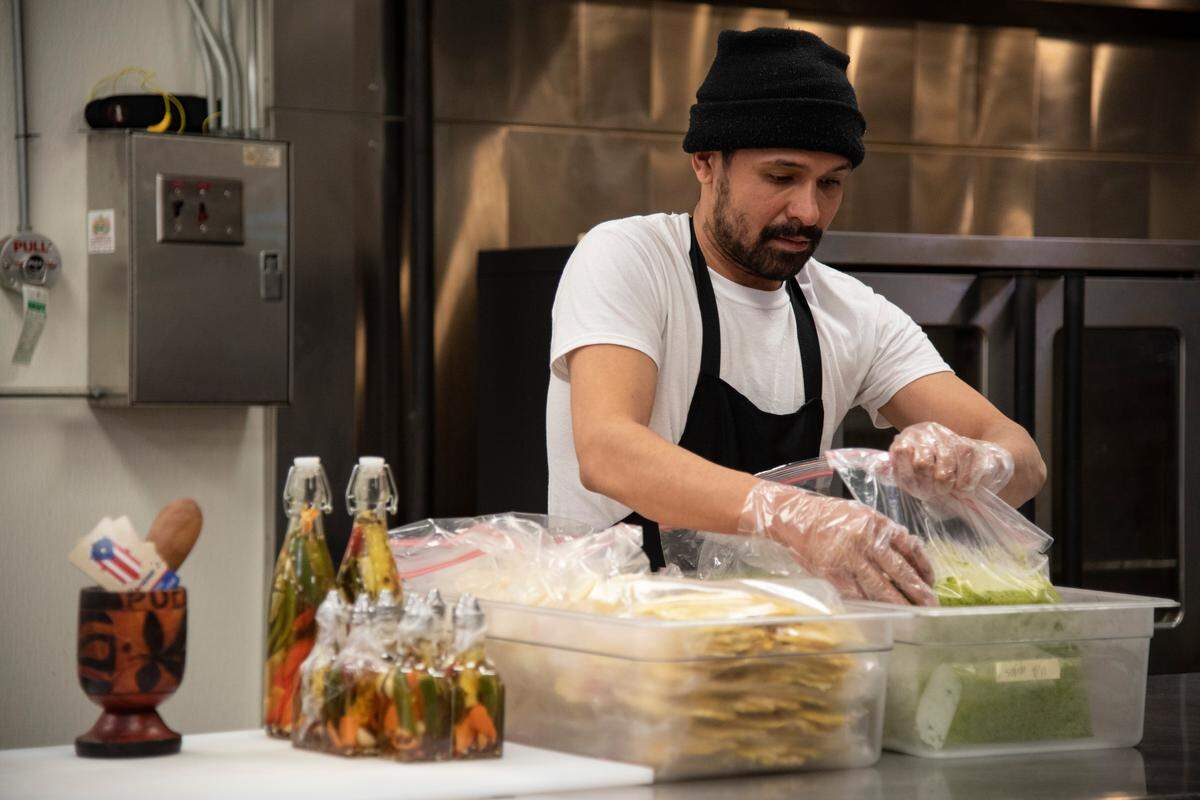 Gavriel Rivera, an owner of Boricua’s, prepares meal orders at Pasco Specialty Kitchen. The food vendor makes authentic family-size Puerto Rican meals to go. Customers pre-order and to pick up and bake, fry or reheat at home.