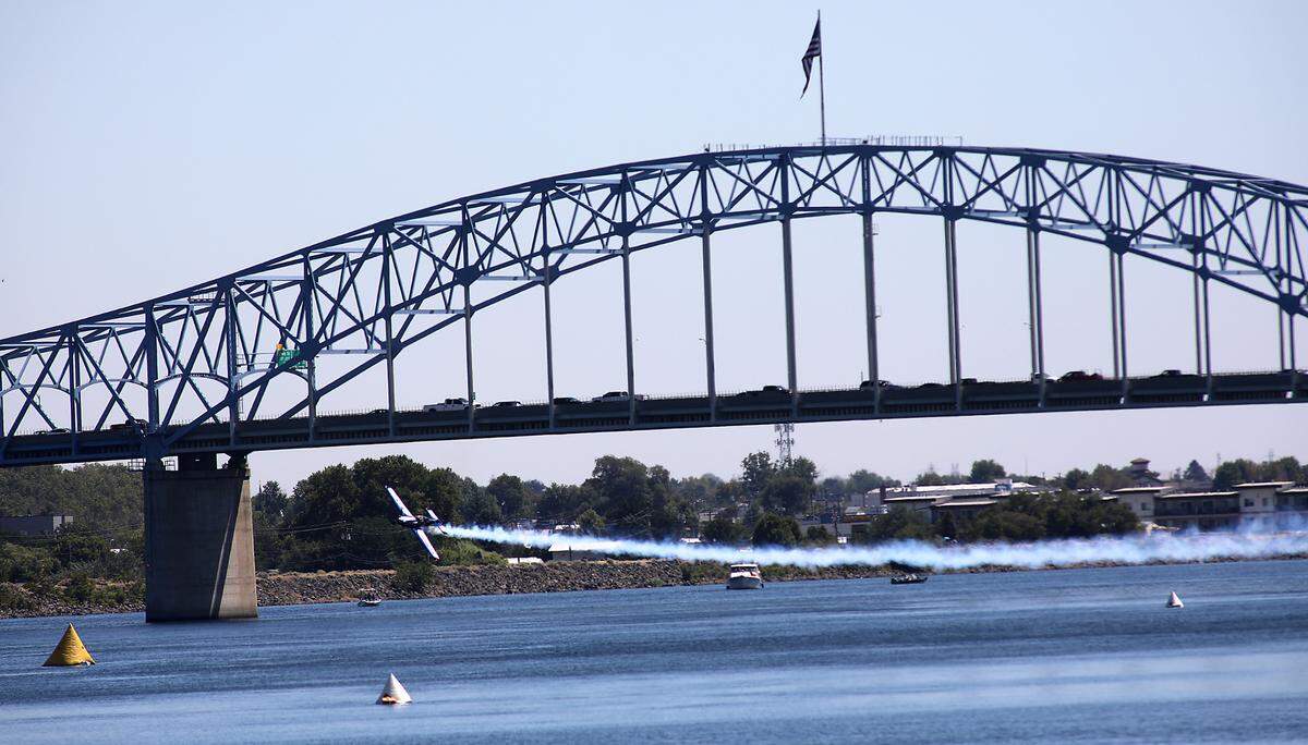 Brad Wursten in his MX2 high-performance acrobtic airplane zips past the blue bridge over the Columbia River during Friday Over-The-River Airshow.