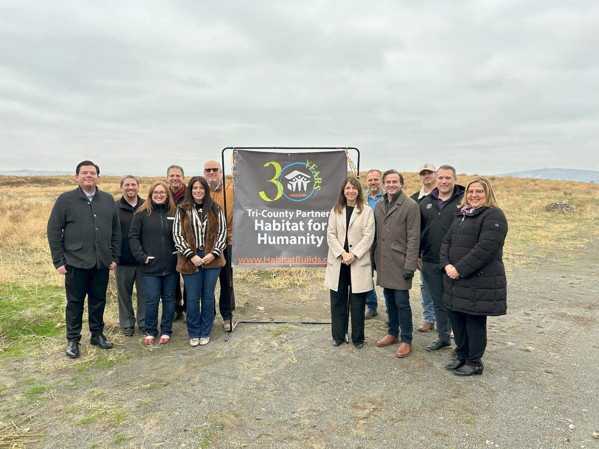 Washington Commissioner of Public Lands Hilary Franz (tan coat) poses for a photo with leaders from Tri-County Partners Habitat for Humanity and the city of Pasco at an announcement for a new Habitat housing initiative leasing Department of Natural Resources land off Road 68 in Pasco.