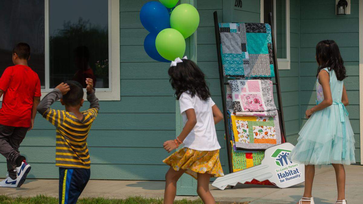 Kids play outside of the Habitat for Humanity Tri-County Partners 144th completed home before a recent dedication ceremony.
