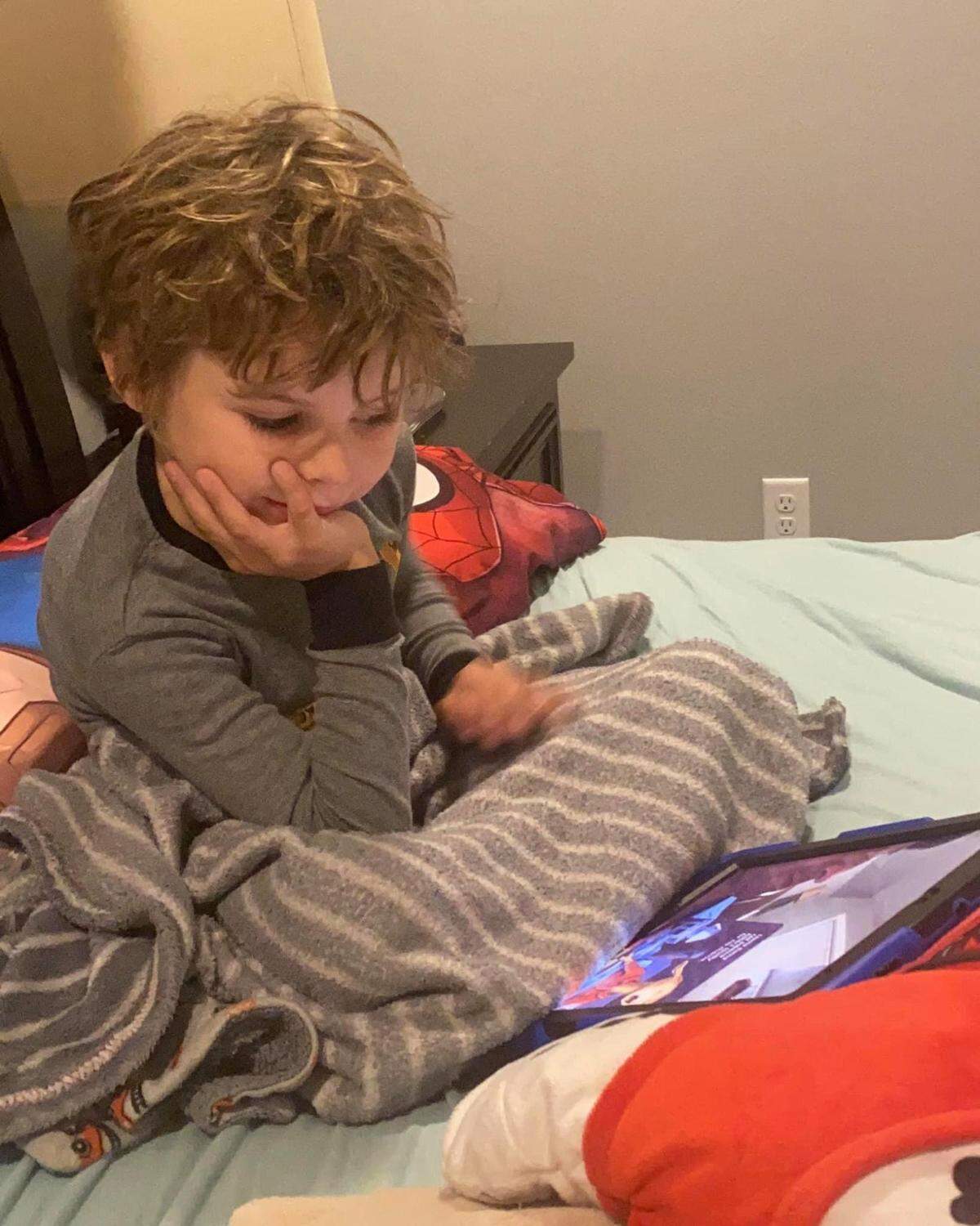 Julie and Shane Webb’s son listens to a story being read by his dad who is quarantined in another room with COVID-19.