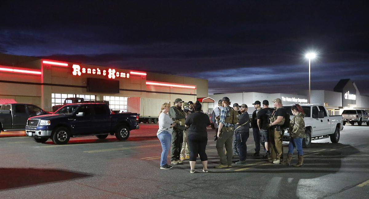 Members of Defend The Tri gather Tuesday night in the parking lot of the Ranch and Home store on Columbia Center Boulevard in Kennewick. Organizers of the group say about 240 members were expected to be stationed Tuesday night at an estimated 30 business locations around the Tri-Cities.