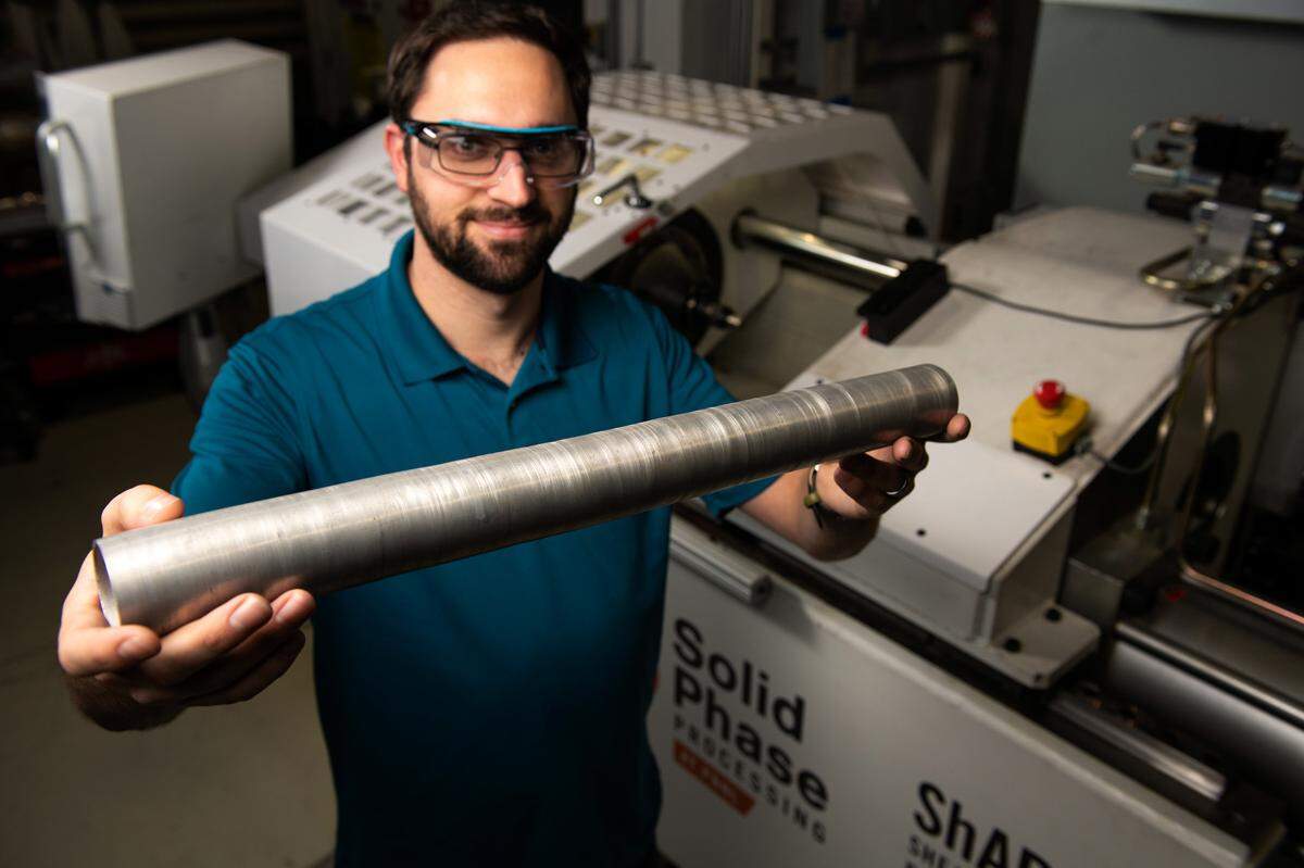PNNL mechanical engineer Brandon Taysom holds a tube manufactured using PNNL’s patented Shear Assisted Processing and Extrusion process — known as ShAPE™ — which makes it possible to produce lighter weight vehicle components and offers a less energy-intensive alternative to conventional manufacturing methods.