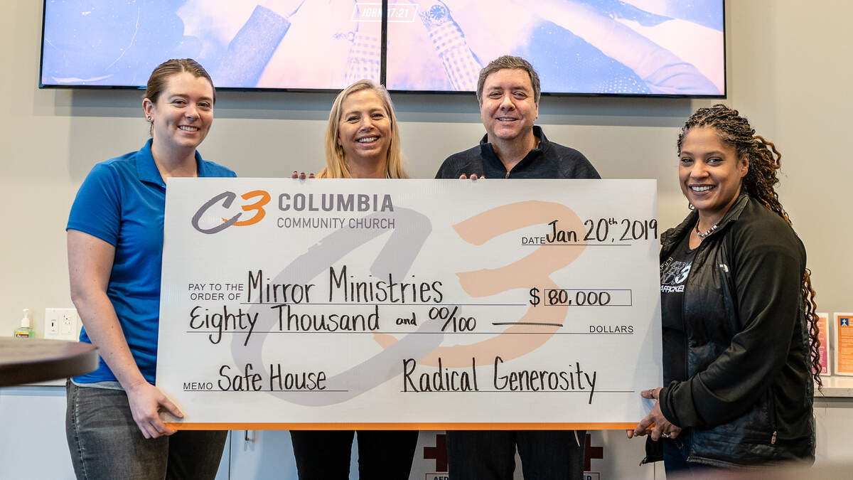 Tricia MacFarlan, executive director of Mirror Ministries, and Pastor Mark Barker of Columbia Community Church, center left and right, after Barker’s church made an $80,000 donation to the nonprofit, which helps sex trafficking survivors.