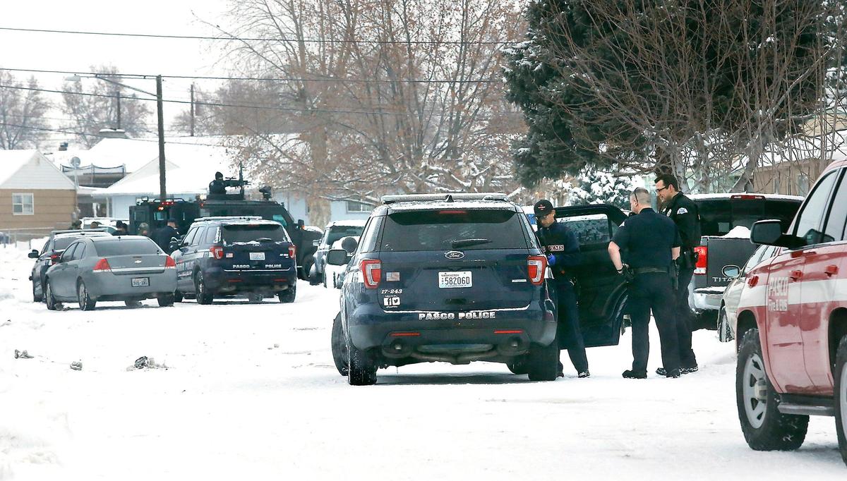 Pasco police officers stand nearby as a Pasco paramedic checks an individual in the back of a patrol vehicle following a standoff in the 1800 block of North 11th Avenue in Pasco. The Tri-City Regional SWAT team responded after officers patrolling the neighborhood heard gun shots around 4 a.m. and observed a male holding a rifle in the doorway of a home before he barricaded himself inside the house. Three male later surrendered peacefully to officers, according to Sgt. Scott Warren of the Pasco Police Department. Watch a video at: tricityherald.com/video
