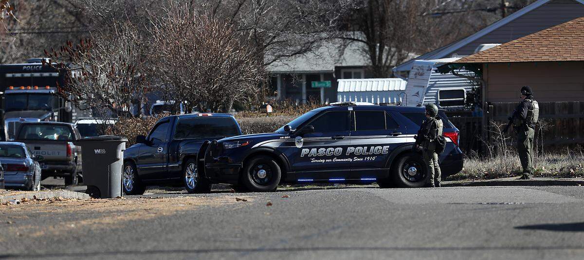 Members of the Tri-City Regional SWAT team surround a home at the intersection of West 6th Place and South Conway Street on Thursday in Kennewick. A wanted suspect was barricaded the home and police were working to get the person to come out, according to a social media post from the department. The standoff is in a neighborhood south of Westgate Elementary School.