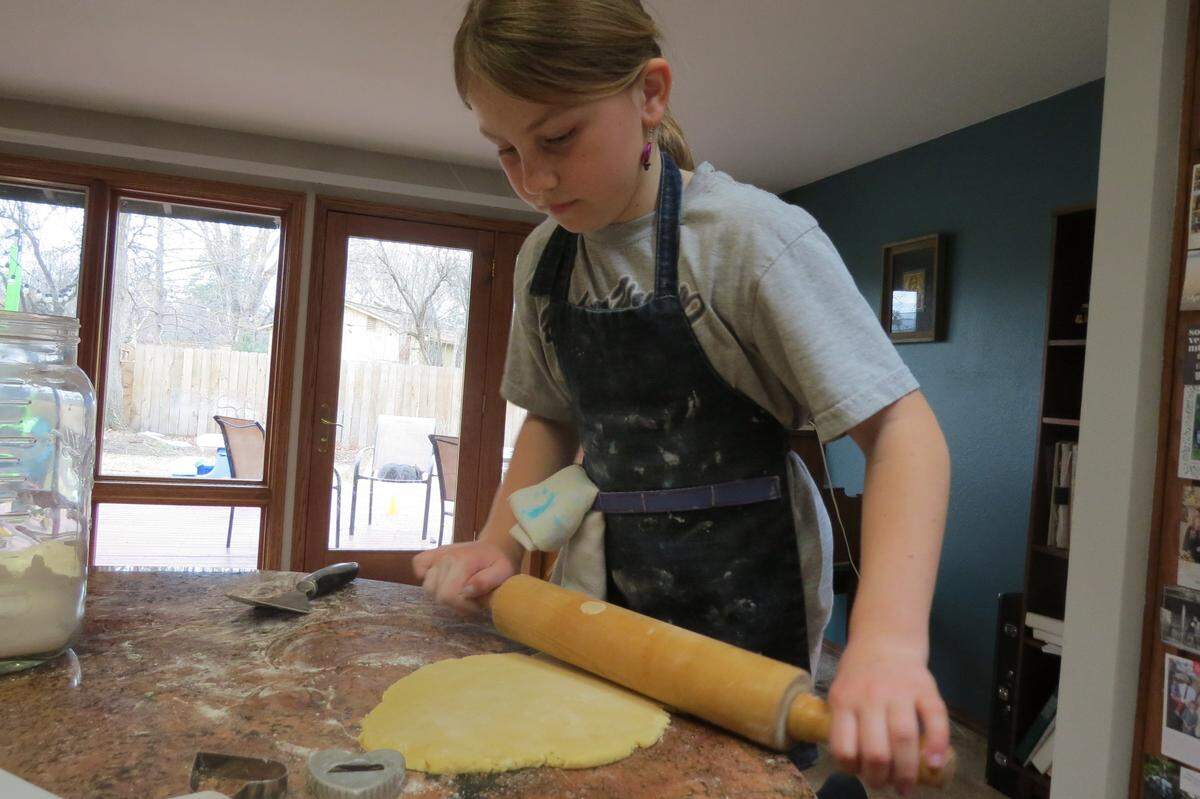 Sage Egbert, 9, rolls out cookie dough as she prepares to make more sugar cookies as part of her effort to help refugees in Ukraine.