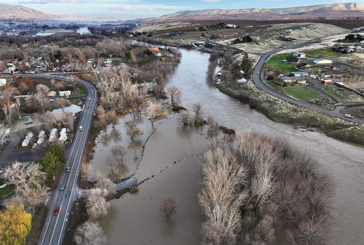 Traffic drives on 1st Street past the road leading the flooded Benton City Recreation Area and Boat Launch Friday morning  just downstream of the bridge across the Yakima River into Benton City.