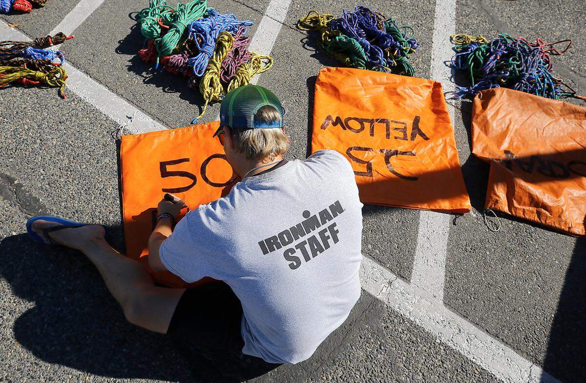 Ironman staff member Tim Dale marks bags while organizing ropes for river marker buoys in the parking lot of the Columbia Point Marina Park in Richland.