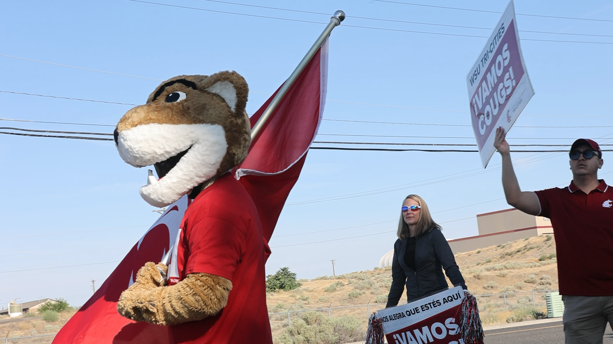 Washington State University’s mascot, Butch, waves a flag Monday as students enter campus for their first day at the Tri-Cities campus.