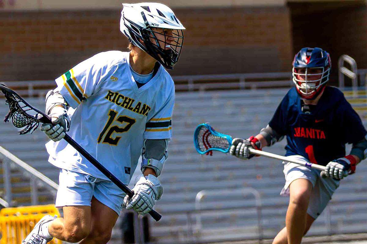 Richland junior Conner Allington (12), who finished with three goals and two assists, advances the ball upfield as Juanita defender No. 1 pursues during the Bombers’ 18-4 playoff win Saturday at Fran Rish Stadium in Richland. 