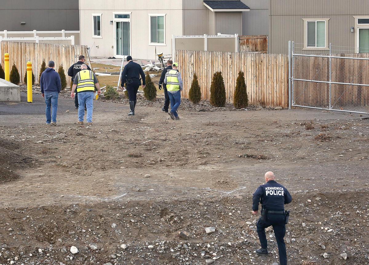 Sgt. Matt Newton climbs the dirt bank of the irrigation wasteway Friday as other traffic officers from the Kennewick Police Department and city surveyors take measurements for their ongoing investigation into the cause of Thursday’s fatal crash at Steptoe Street and 10th Avenue.