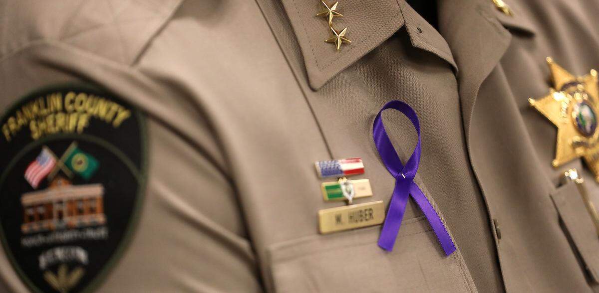 Members of the Franklin County Sheriff Office wear purple ribbons as Sheriff Jim Raymond announces the arrest of Jesse Lee Castillo, 51, in the 1997 murder of 13-year-old Anna Pelayo. Purple was her favorite color.