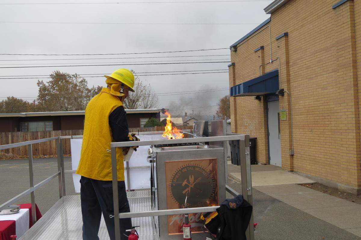 Pasco firefighter Ben Shearer demonstrates how to handle a cooking fire Monday morning at Pasco’s new demonstration trailer.