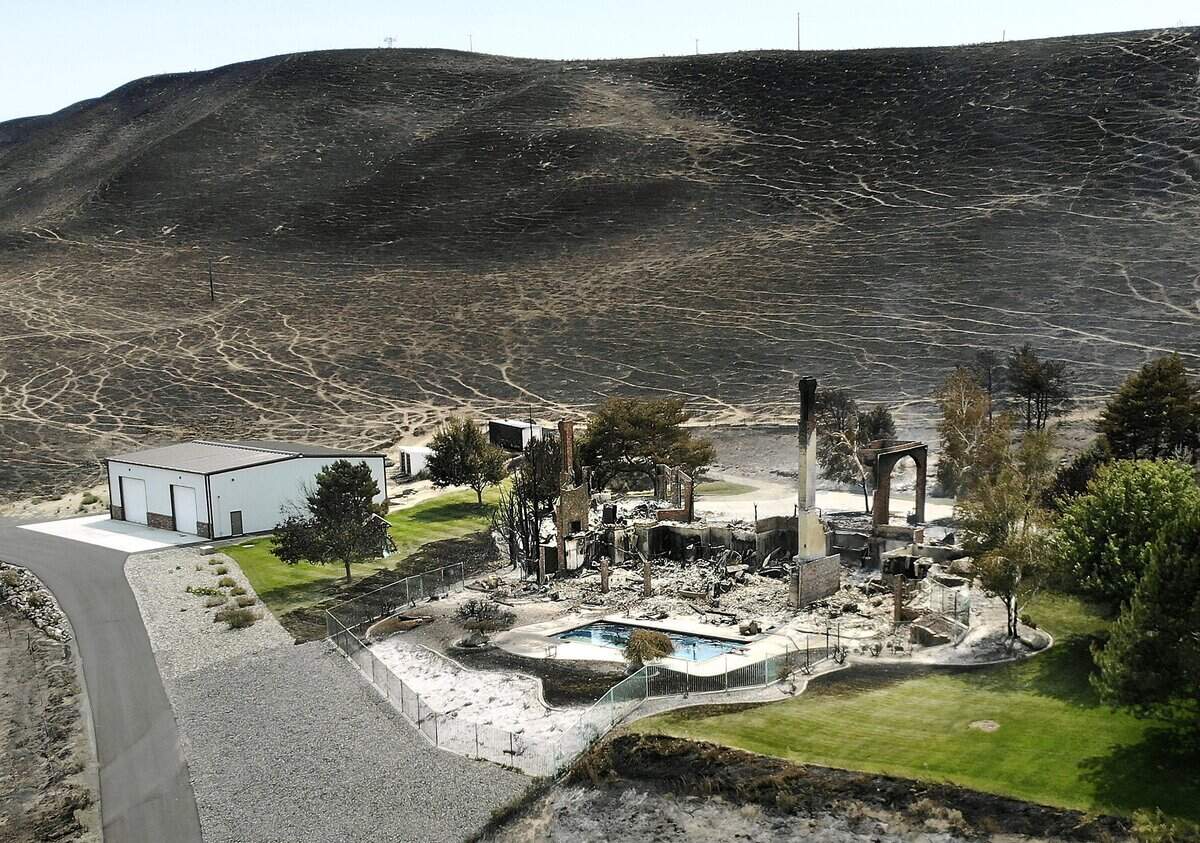 Brick columns are the only thing left standing of this house Sunday at the south end of South Ely Street after a devastating wind-driven fire swept across the hill in South Kennewick from the Bofer Canyon Road area the previous day. A swiiming pool and an apparently undamaged metal building stand out from the scorched landscape. Watch a video at: tricityheral.com/video